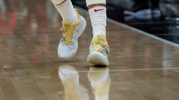 View of white and gold New Balance shoes.